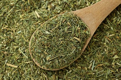 Photo of Pile of dried dill and wooden spoon, top view
