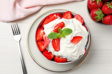 Photo of Delicious strawberries with whipped cream served on white wooden table, flat lay