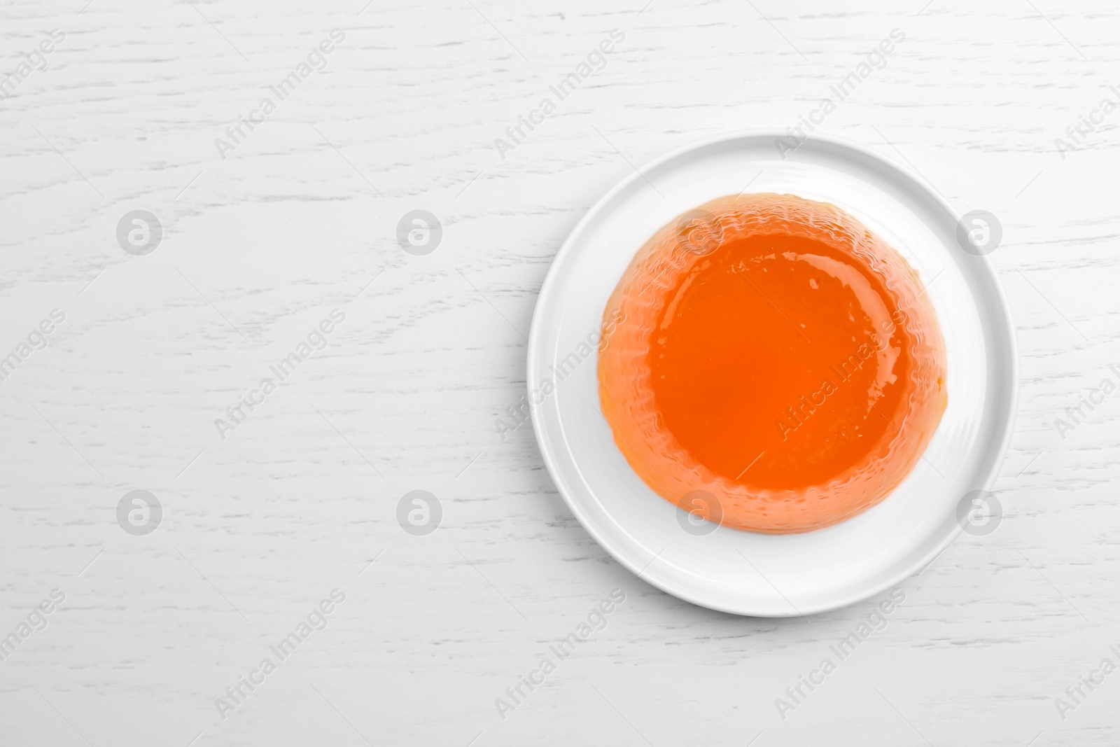 Photo of Plate with tasty fruit jelly on white wooden table, top view. Space for text