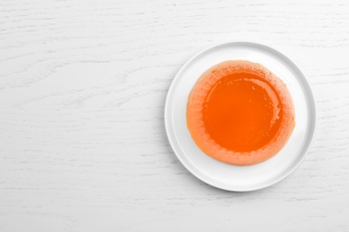 Photo of Plate with tasty fruit jelly on white wooden table, top view. Space for text