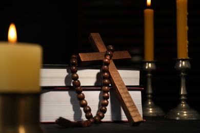 Church candles, Bible, rosary beads and cross on table