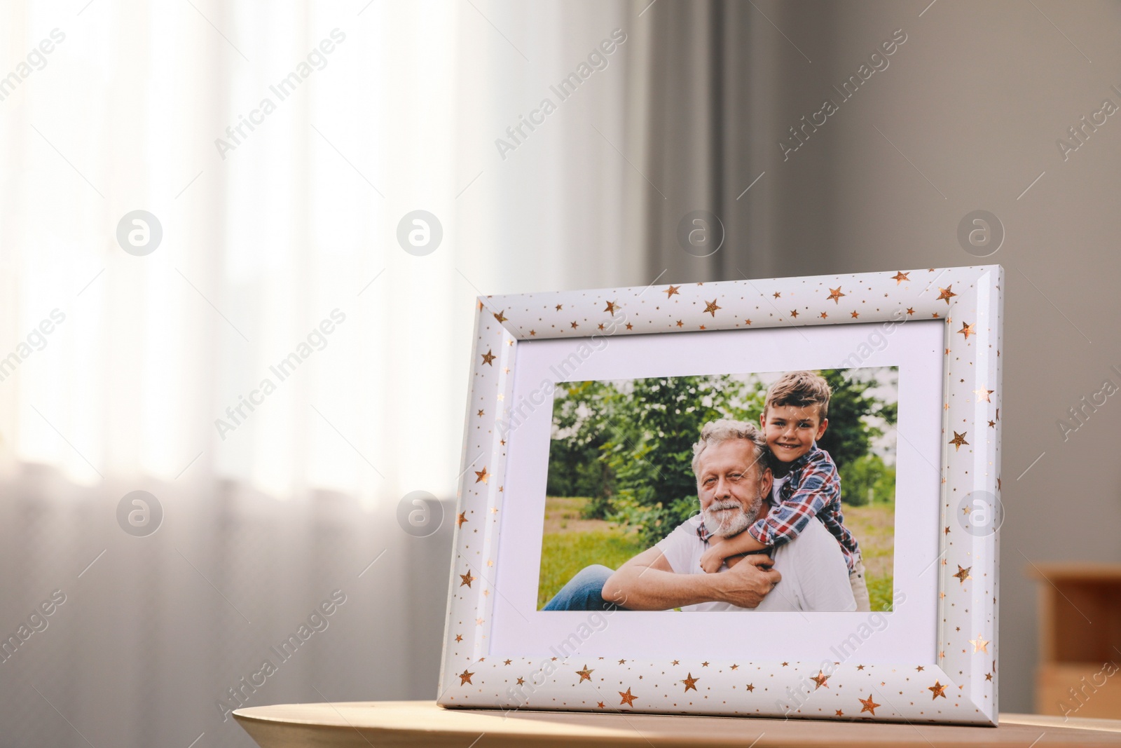 Photo of Framed family photo on wooden table in room. Space for text