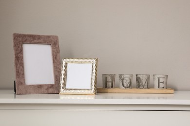 Photo of Empty photo frames and candles on table indoors, space for text