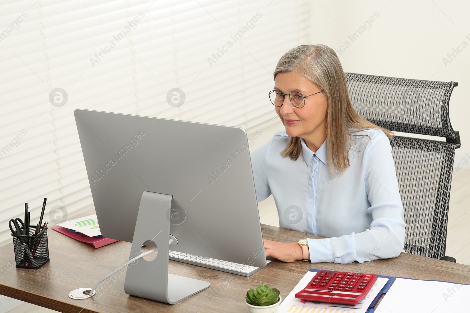 Photo of Senior accountant working at wooden desk in office