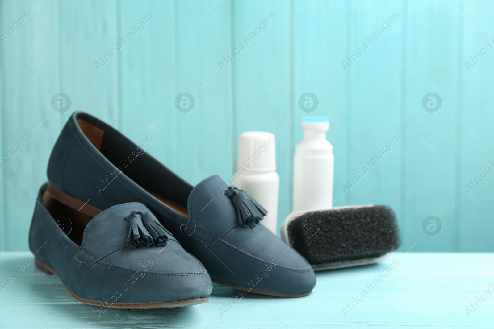 Photo of Stylish footwear with shoe care accessories on light blue wooden table