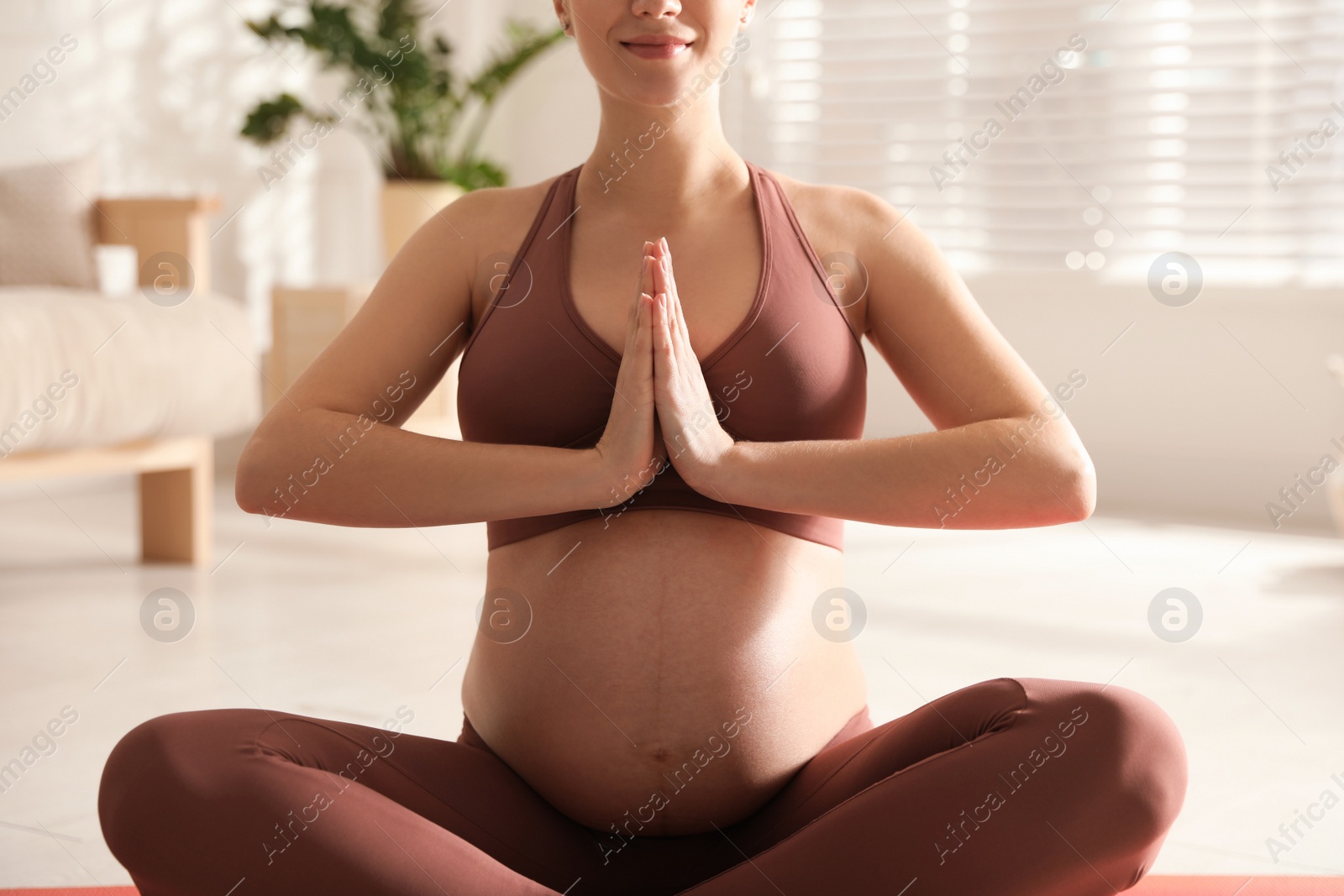 Photo of Young pregnant woman practicing yoga at home, closeup