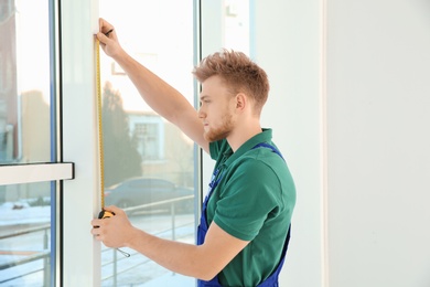 Service man measuring window for installation indoors