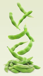 Image of Raw green edamame pods falling onto pile against color background