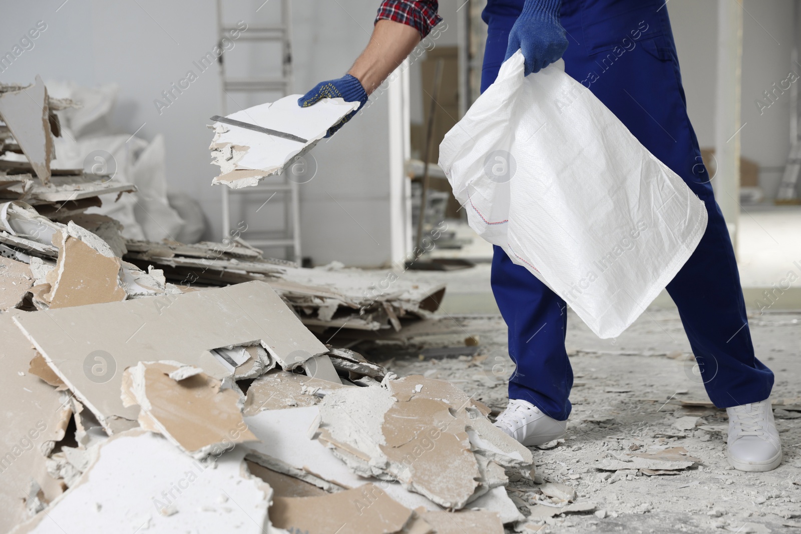 Photo of Construction worker with used building materials in room prepared for renovation, closeup