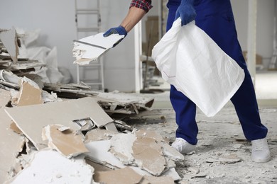 Construction worker with used building materials in room prepared for renovation, closeup