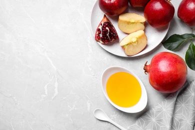 Photo of Honey, apples and pomegranate on marble table, flat lay with space for text. Rosh Hashanah holiday