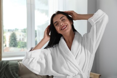 Photo of Beautiful young woman wearing white bathrobe indoors