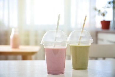 Photo of Tasty fresh milk shakes in plastic cups on white table indoors