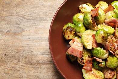 Image of Delicious fried Brussels sprouts with bacon in on wooden table, top view