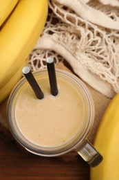 Photo of Mason jar with banana smoothie on wooden table, flat lay