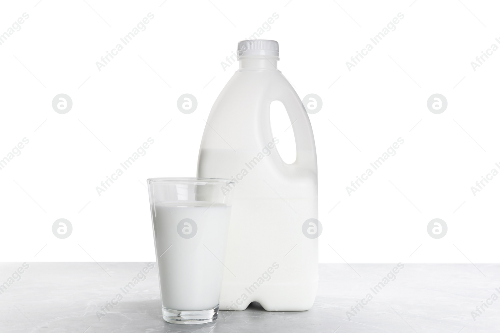 Photo of Gallon bottle of milk and glass on light grey table