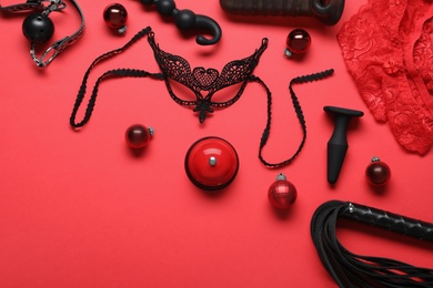 Set of different sex toys and Christmas balls on red background, flat lay