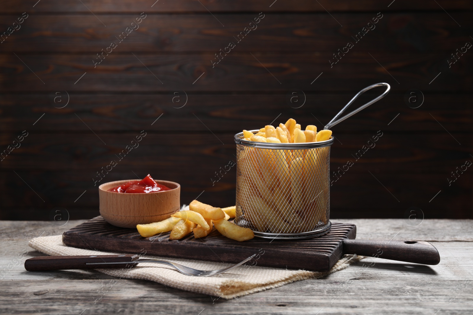 Photo of Tasty French fries and ketchup on light grey wooden table