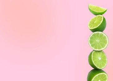 Image of Stacked cut limes on light pink background, space for text