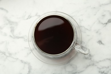 Photo of Hot coffee in cup on white marble table, top view
