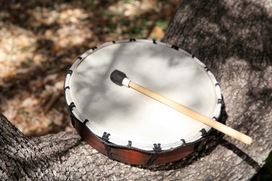 Photo of Drum with mallet on tree bark outdoors. Percussion musical instrument