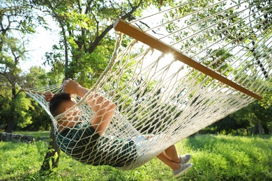 Photo of Young man resting in comfortable hammock at green garden