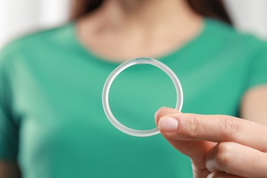 Photo of Woman holding diaphragm vaginal contraceptive ring on blurred background, closeup