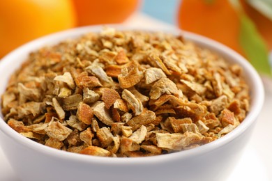 Bowl of dried orange zest seasoning and fresh fruits, closeup