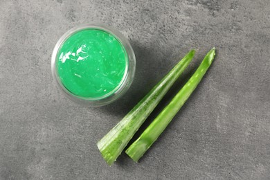 Photo of Bowl with natural gel and aloe vera leaves on grey table, flat lay