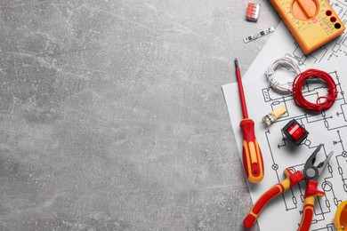 Flat lay composition with wiring diagrams and digital multimeter on grey table, space for text