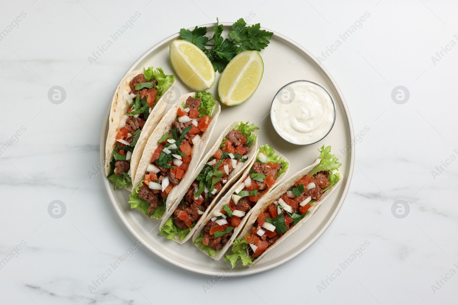 Photo of Delicious tacos with meat and vegetables served on white marble table, top view