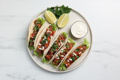 Delicious tacos with meat and vegetables served on white marble table, top view