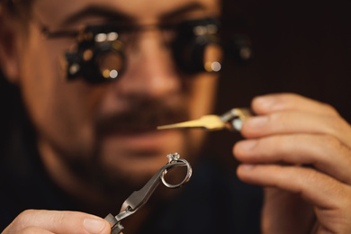 Photo of Jeweler working with ring on blurred background, closeup