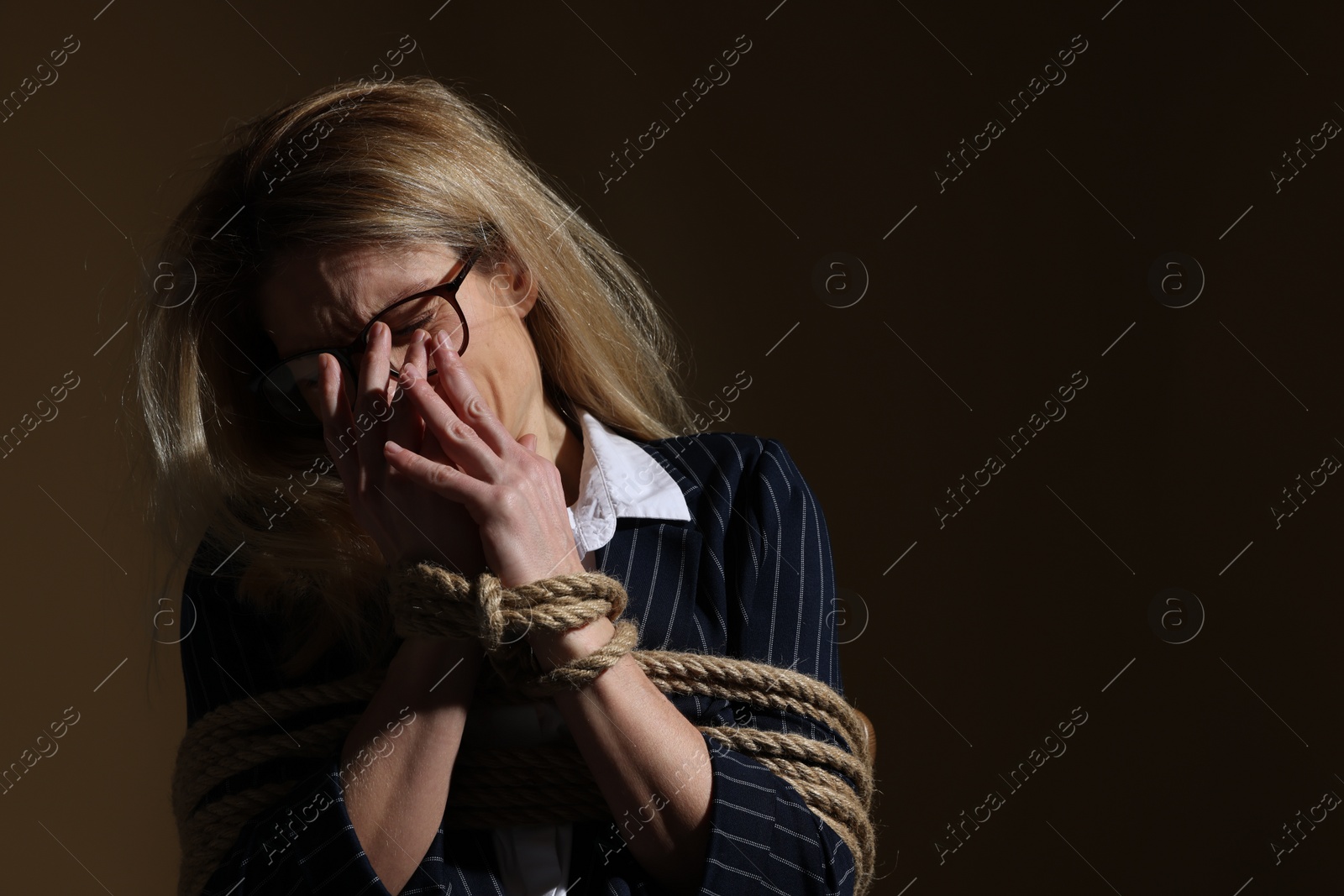 Photo of Woman tied up and taken hostage on dark background. Space for text