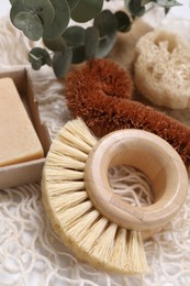 Photo of Cleaning brushes, loofah, soap bar and eucalyptus leaves on table, closeup