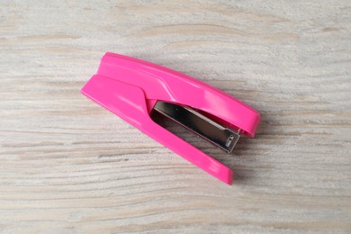 One pink stapler on wooden table, top view