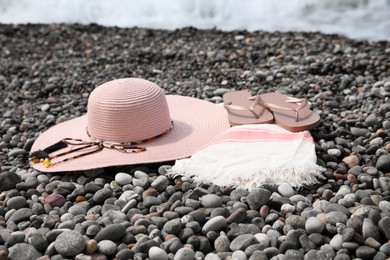 Photo of Beautiful hat and flip flops on pebble beach