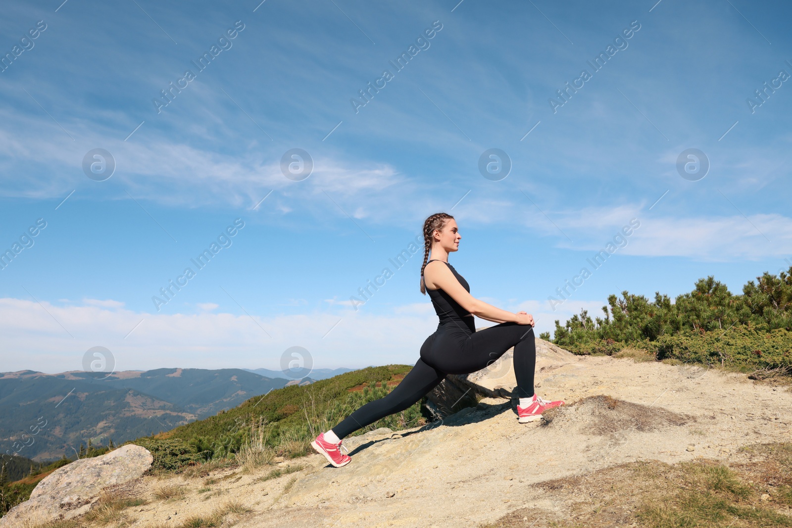 Photo of Beautiful young woman stretching in mountains on summer morning