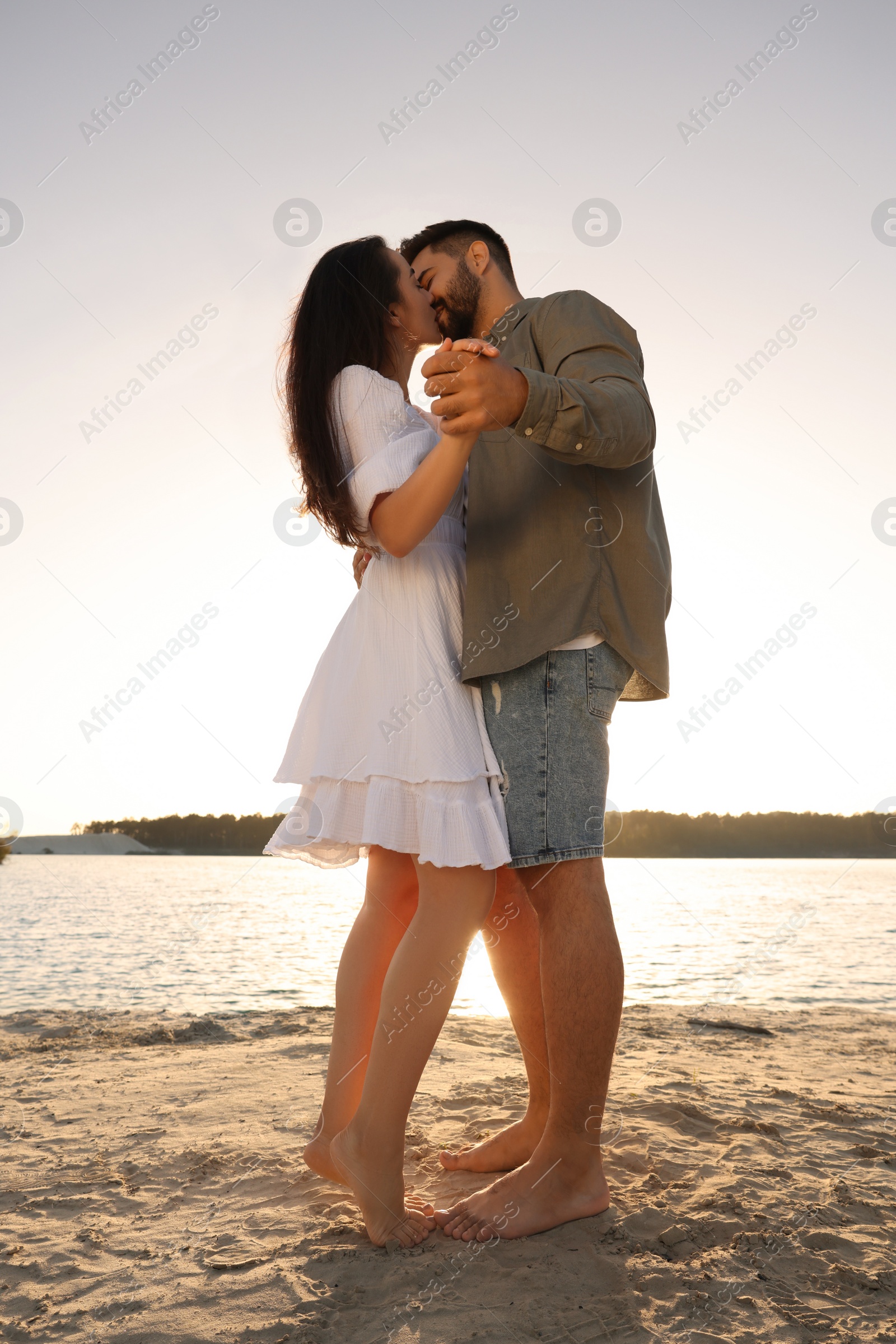 Photo of Beautiful couple dancing and kissing near river, low angle view
