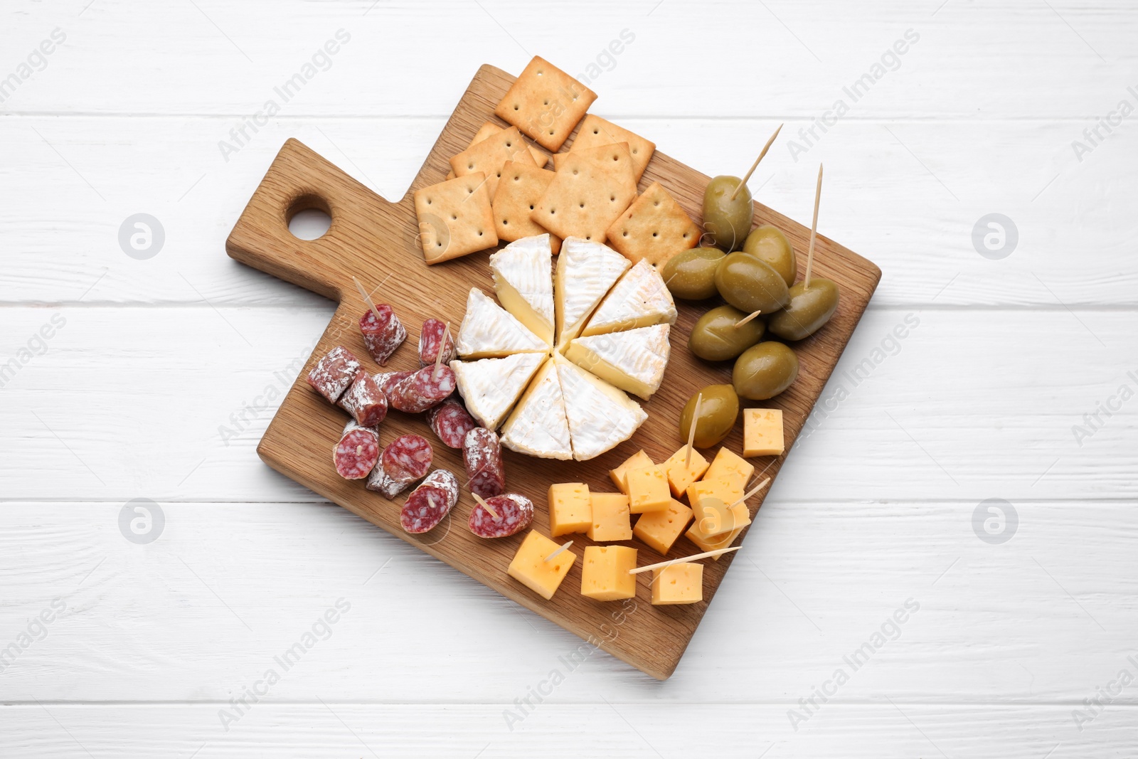 Photo of Toothpick appetizers. Pieces of sausage, cheese and olives on white wooden table, top view