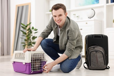 Photo of Travel with pet. Man closing carrier with cat at home