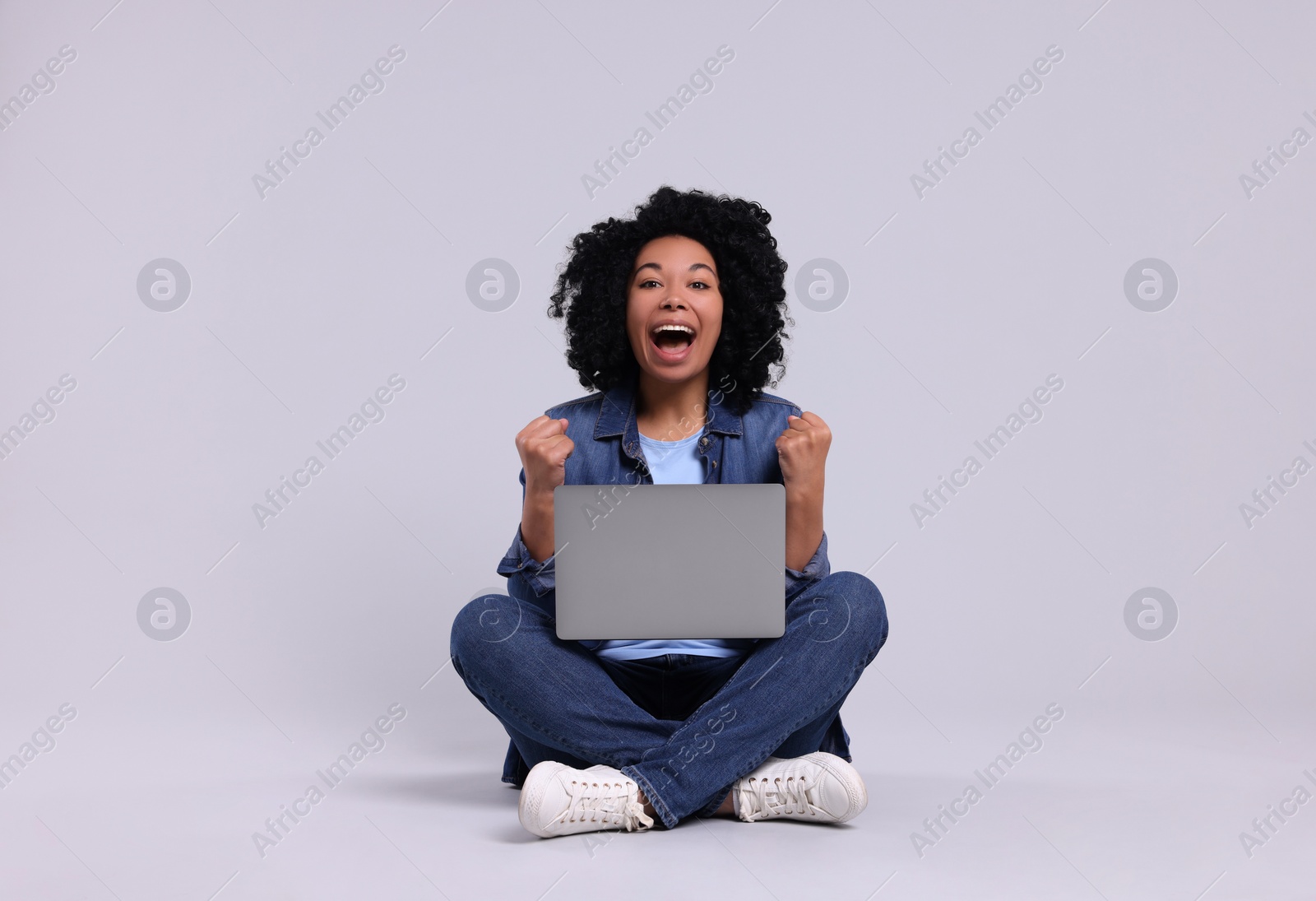 Photo of Emotional young woman with laptop on light grey background