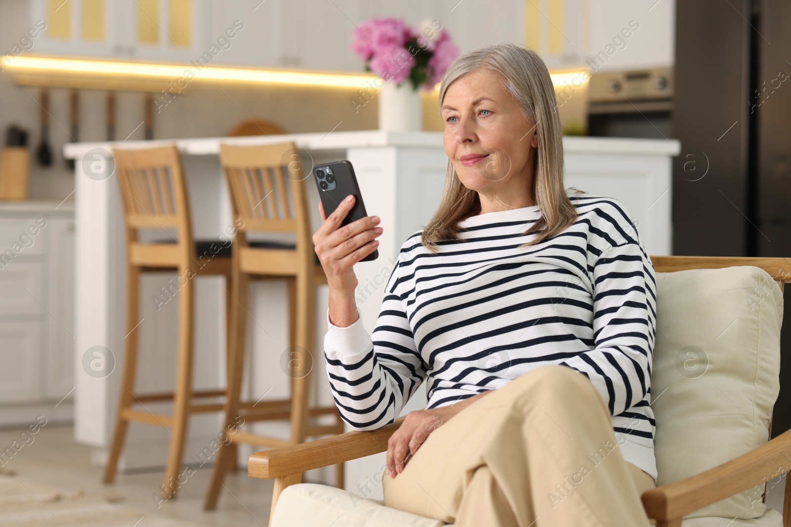 Photo of Senior woman using mobile phone at home, space for text