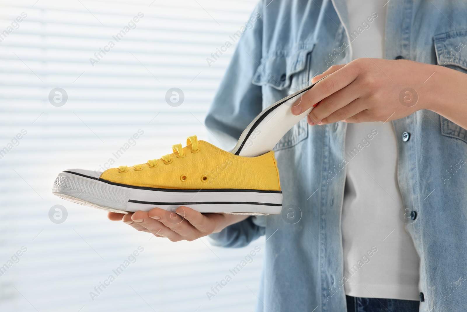 Photo of Woman putting orthopedic insole into shoe indoors, closeup. Foot care