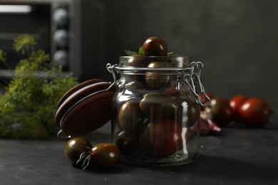 Photo of Pickling jar with fresh tomatoes on black kitchen table, closeup