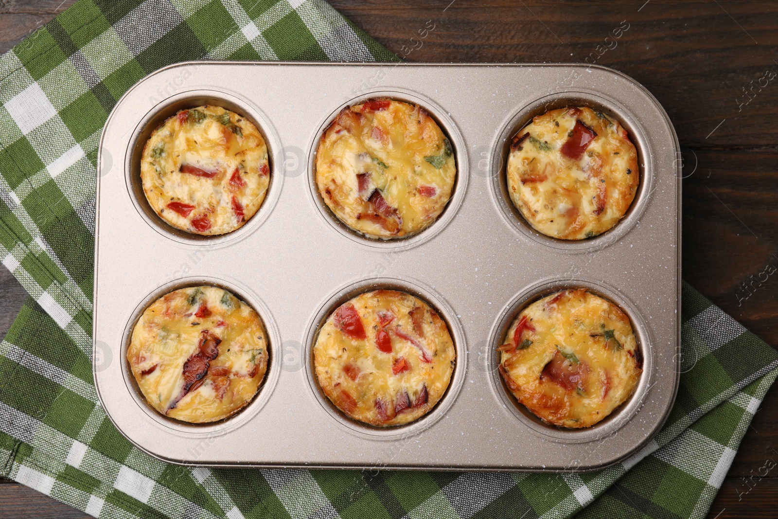 Photo of Freshly baked bacon and egg muffins with cheese in tin on table, top view