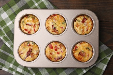 Photo of Freshly baked bacon and egg muffins with cheese in tin on table, top view