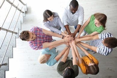 Photo of People putting hands together indoors. Unity concept
