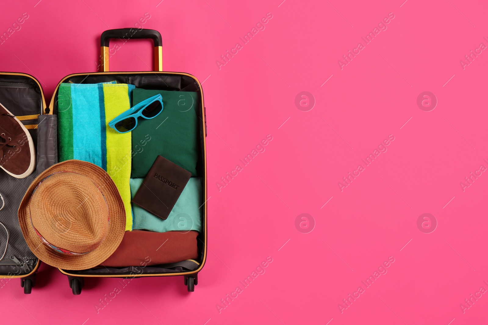 Photo of Open suitcase with traveler's belongings on color background, top view. Space for text