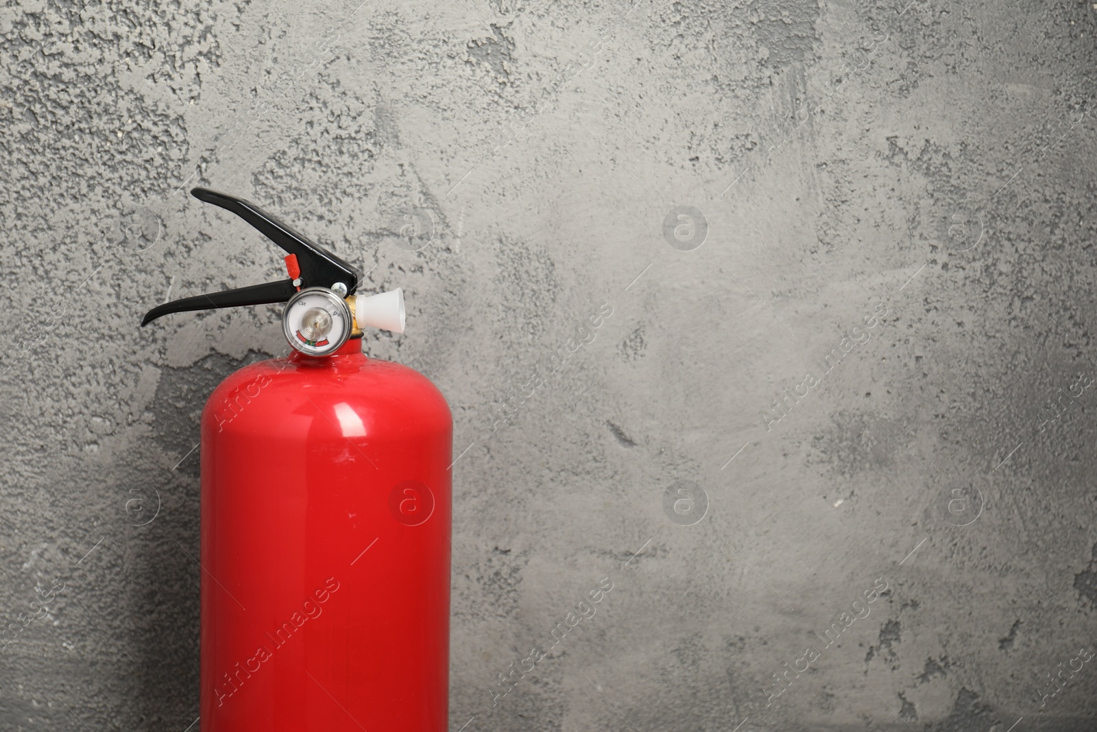 Photo of Fire extinguisher on grey textured background, space for text